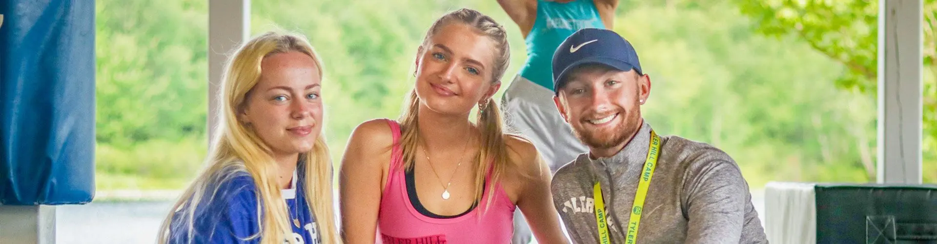 Two girls and a guy smile for photo with green background