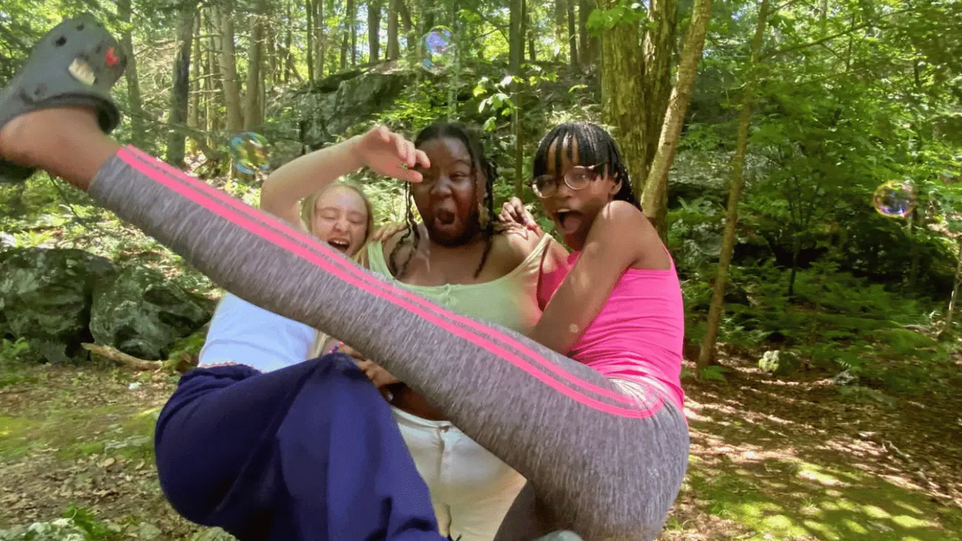 Three girls laughing in the woods at summer camp 