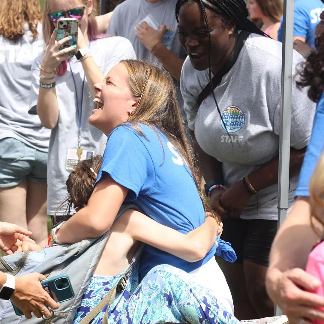 A in blue girl laughs while holding a camper