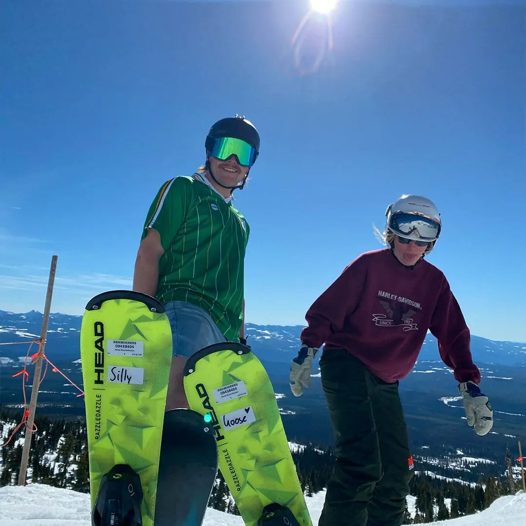 Guy and girl smile on snowy mountain with skis